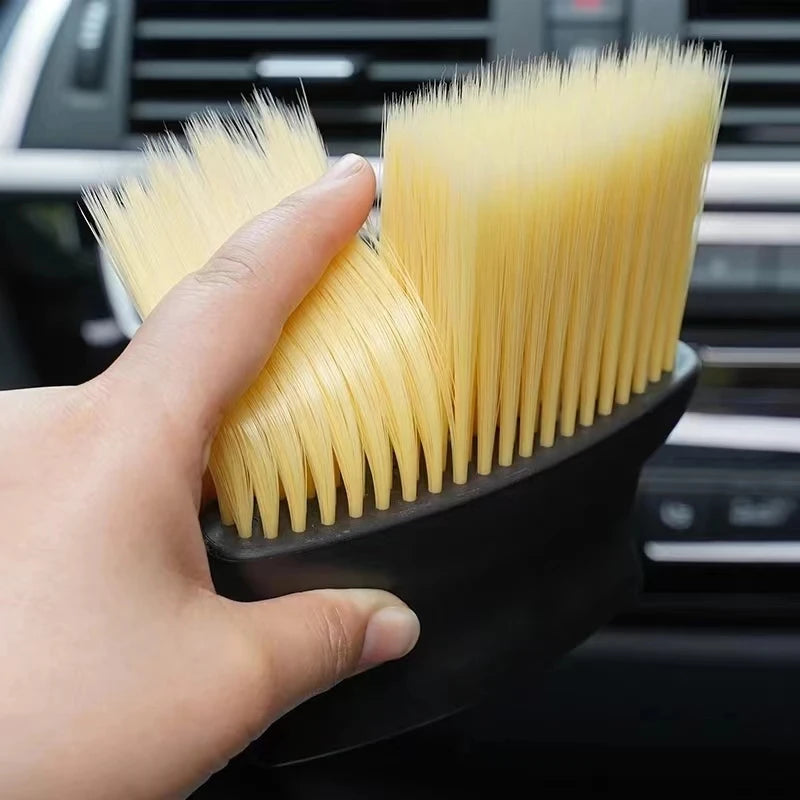 portable handheld car interior cleaning brush resting on automotive leather