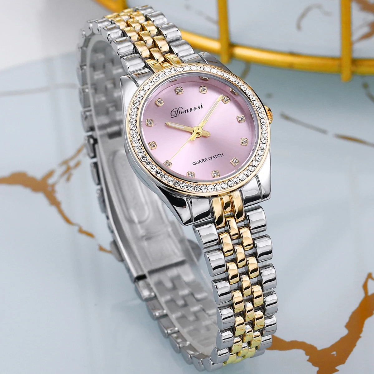Close up of a luxury quartz watch with a geometric diamond style dial face, minimalist design, and metallic strap.