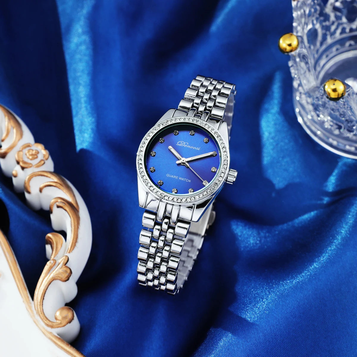 Close up of a luxury quartz watch with a geometric diamond style dial face, minimalist design, and metallic strap.